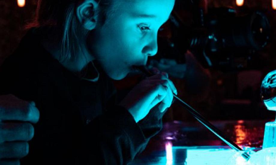 Blue light reflects on child blowing bubbles on a lightbox