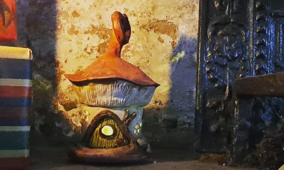 Ceramic gnome home hiding by fireplace in museum